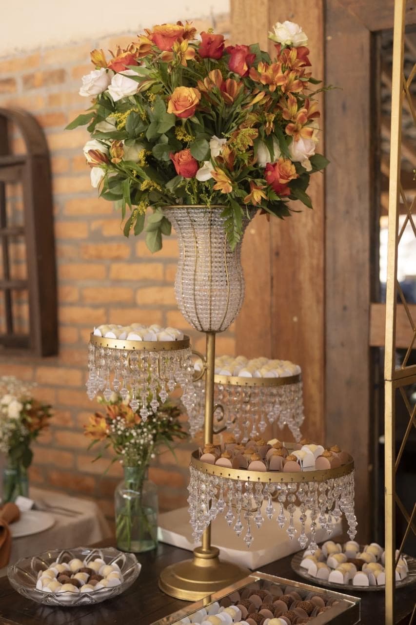 Doces, cristais e arranjo floral em mesa de festa